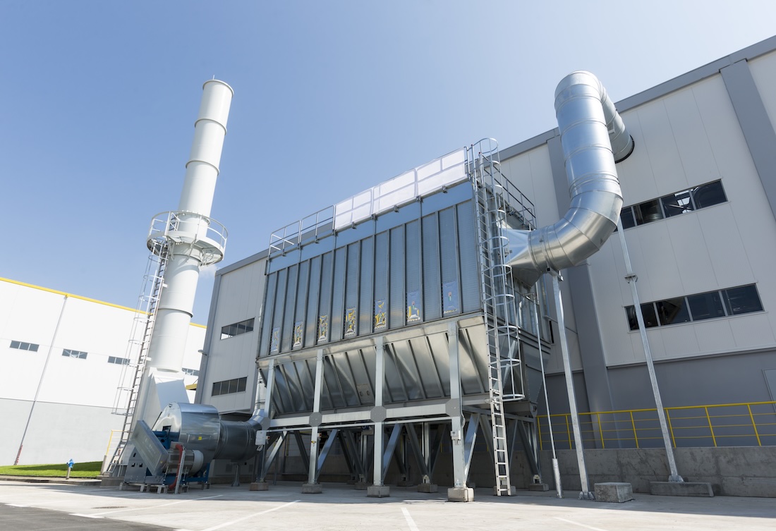 A baghouse dust collector attached to a manufacturing facility.